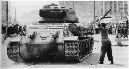 Ein Mann schlgt mit einer Eisenstange auf einen sowjetischen Panzer ein.
